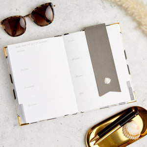 Hello Day weekly 2024 planner diary with grey bookmark, sunglasses and pens in tray
